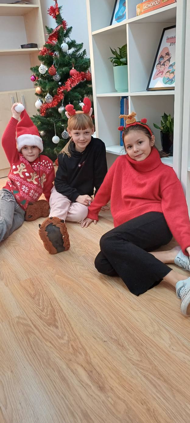 dziewczynki w świątecznych ubraniach siedzą obok choinki 22. 12. 2025 01